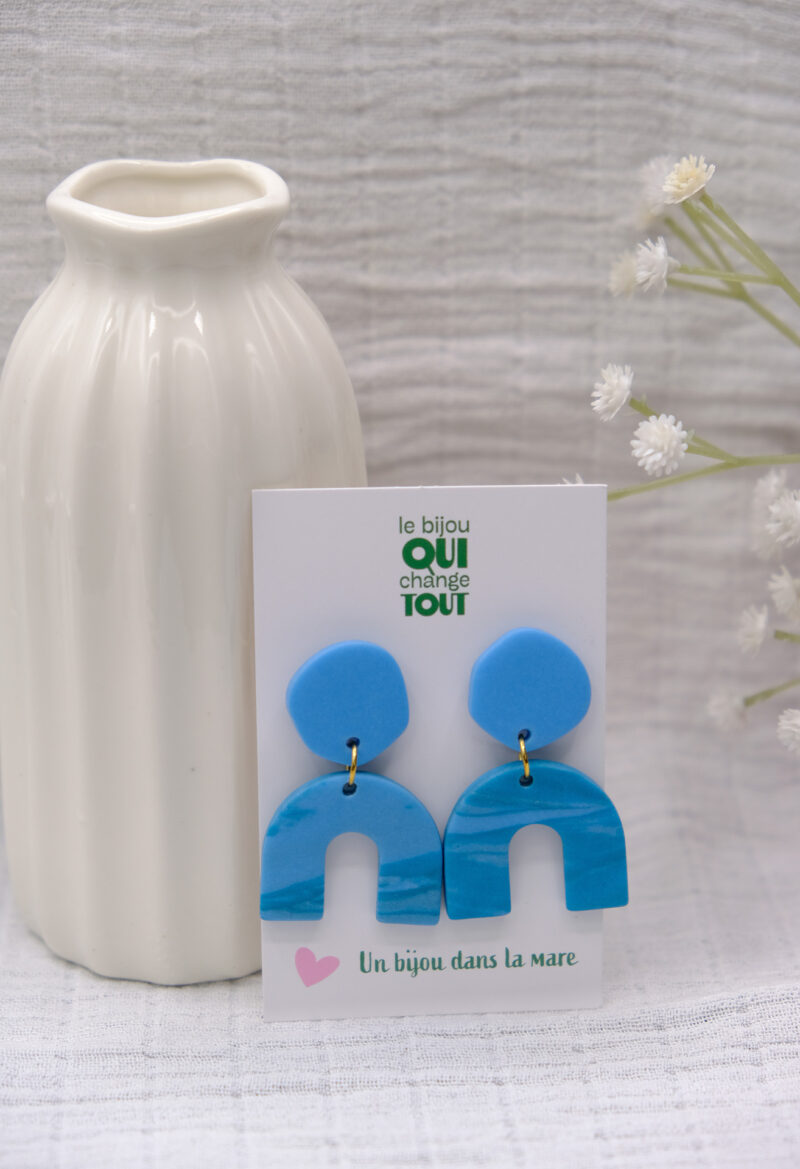 Les boucles d’oreilles pendantes Queta se distinguent par leur design à la fois moderne et bohème. Composées d’un rond asymétrique et d’une arche, elles insufflent une touche bohème et raffinée à votre tenue. Façonnées à la main en argile polymère et acier inoxydable plaqué or 18 carats, les Queta allient savoir-faire artisanal et matériaux de qualité. Imposantes par leur taille, mais légères à porter, elles apportent du caractère tout en sublimant votre allure avec finesse. Les boucles d’oreilles Queta existent en 3 coloris sur le site d'Un Bijou dans la Mare.