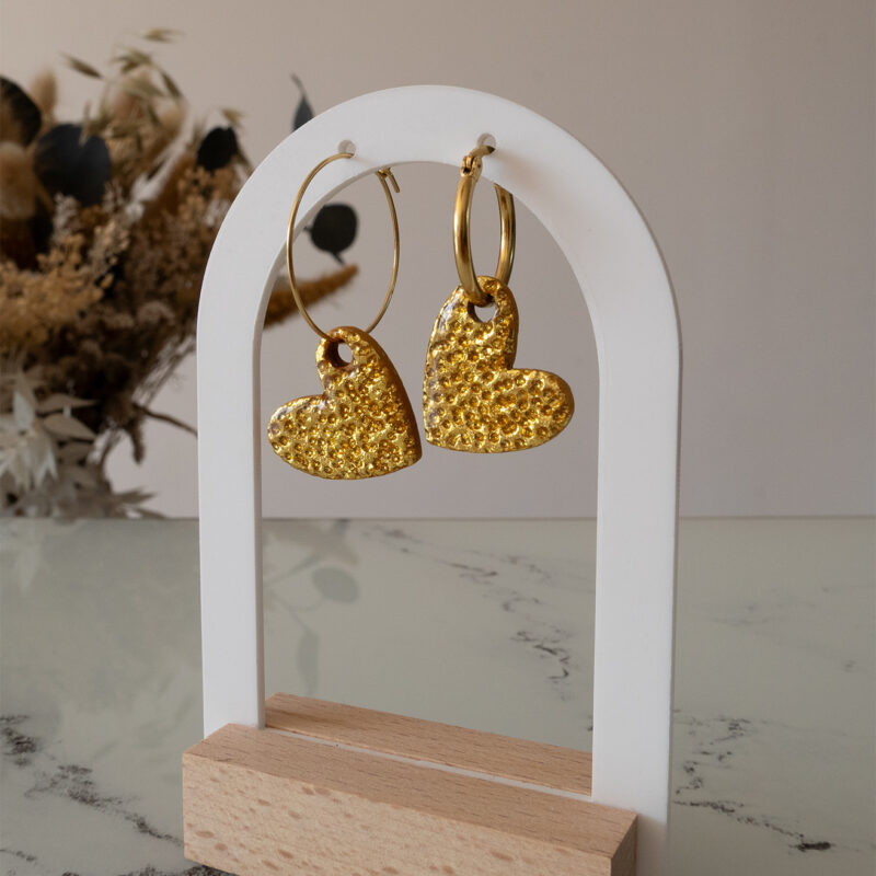 Apportez une touche d’élégance romantique à votre tenue grâce aux créoles avec cœur interchangeable, Aimée. Ces boucles d’oreilles artisanales se distinguent par un joli cœur asymétrique en feuille d'or martelé à la main, posé sur une créole dorée ou argentée à choisir selon vos préférences. Polyvalentes, ultra légères et confortables, elles sublimeront aussi bien une tenue décontractée qu’un style plus sophistiqué.