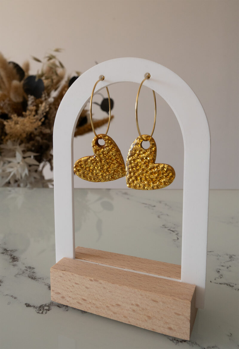 Apportez une touche d’élégance romantique à votre tenue grâce aux créoles avec cœur interchangeable doré, Aimée. Ces boucles d’oreilles artisanales se distinguent par un joli cœur asymétrique en feuille d'or martelé à la main, posé sur une créole dorée ou argentée à choisir selon vos préférences. Polyvalentes, ultra légères et confortables, elles sublimeront aussi bien une tenue décontractée qu’un style plus sophistiqué.