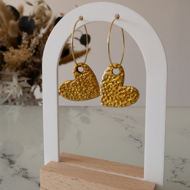 Apportez une touche d’élégance romantique à votre tenue grâce aux créoles avec cœur interchangeable doré, Aimée. Ces boucles d’oreilles artisanales se distinguent par un joli cœur asymétrique en feuille d'or martelé à la main, posé sur une créole dorée ou argentée à choisir selon vos préférences. Polyvalentes, ultra légères et confortables, elles sublimeront aussi bien une tenue décontractée qu’un style plus sophistiqué.