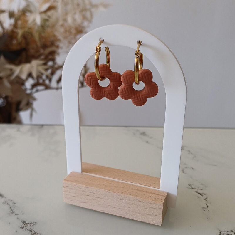 Apportez une touche poétique à vos looks avec les créoles avec fleurs interchangeables April. Ces boucles d’oreilles délicates se distinguent par une fine fleur à cinq pétales, de couleur terracotta et avec une joli texture, posée sur une créole à choisir selon vos préférences. Inspirées par la nature, polyvalentes et confortables, elles sublimeront aussi bien une tenue décontractée qu’un style plus sophistiqué. Elles sont réversibles,