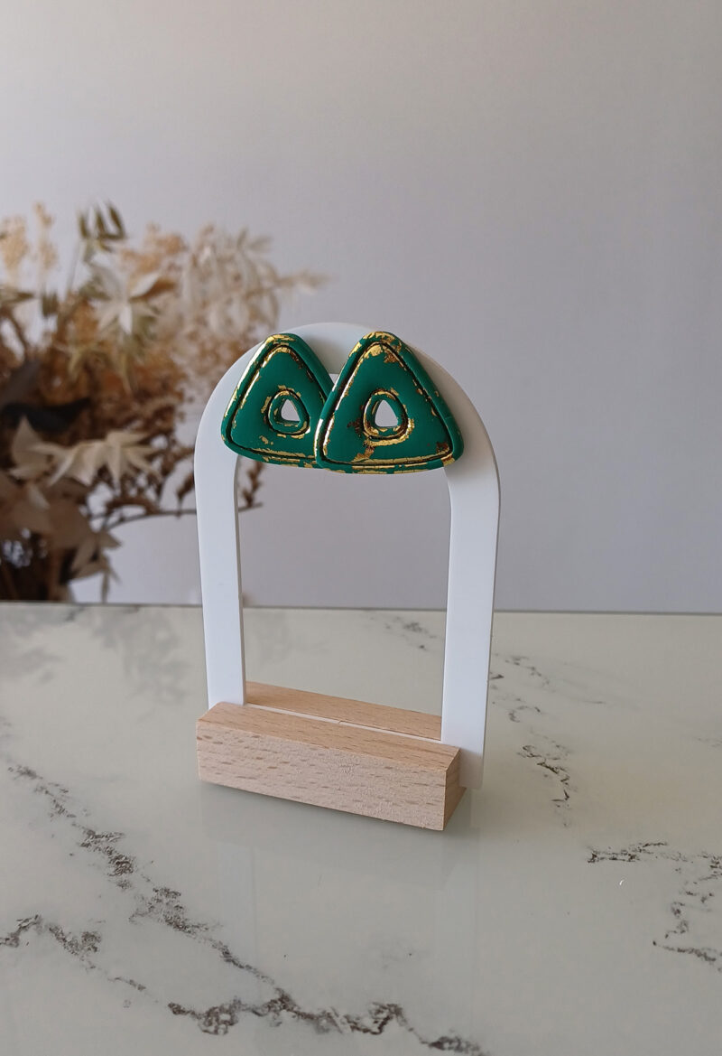 Laissez-vous séduire par Clarisse, des puces d’oreilles audacieuses et raffinées qui mêlent modernité et sophistication. Leur forme triangulaire, généreuse et texturée, est sublimée par des rainures délicates et des touches de feuille d’or, révélées comme si le vert mat avait été gratté pour dévoiler un éclat précieux. Imposantes mais légères, les puces d’oreilles Clarisse offrent un parfait équilibre entre caractère et élégance. Idéales pour celles qui souhaitent affirmer leur singularité avec un bijou artisanal, pensé pour illuminer chaque moment de votre vie. Un hommage à la beauté brute et à l’art du détail.