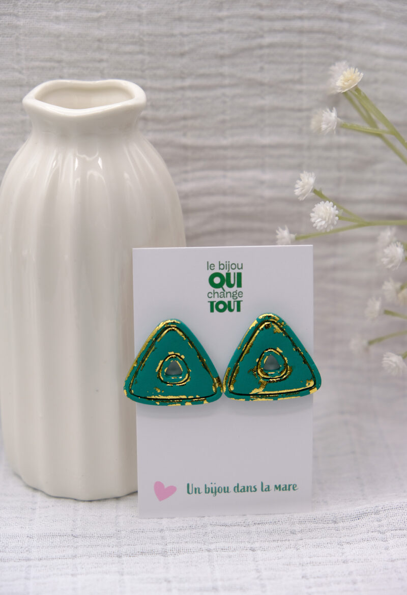 Laissez-vous séduire par Clarisse, des puces d’oreilles audacieuses et raffinées qui mêlent modernité et sophistication. Leur forme triangulaire, généreuse et texturée, est sublimée par des rainures délicates et des touches de feuille d’or, révélées comme si le vert mat avait été gratté pour dévoiler un éclat précieux. Imposantes mais légères, les puces d’oreilles Clarisse offrent un parfait équilibre entre caractère et élégance. Idéales pour celles qui souhaitent affirmer leur singularité avec un bijou artisanal, pensé pour illuminer chaque moment de votre vie. Un hommage à la beauté brute et à l’art du détail.