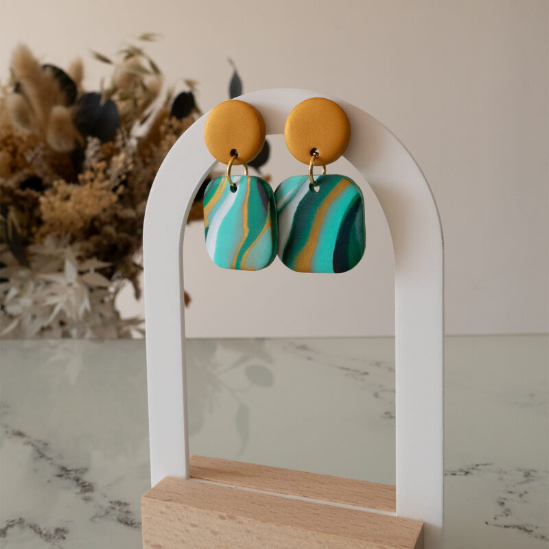 Ajoutez une touche de modernité minimaliste à votre style avec les boucles d’oreilles faites main Élodie. Ces pièces uniques associent un rond d’un beau doré nacré à un carré aux bords arrondis, marbré avec 3 couleurs de vert différents, du blanc du noir et du doré nacré. Parfaites pour toutes les occasions, elles apportent une subtilité contemporaine à vos tenues, qu’elles soient casual ou habillées.