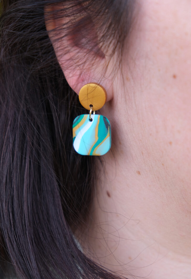 Ajoutez une touche de modernité minimaliste à votre style avec les boucles d’oreilles faites main Élodie. Ces pièces uniques associent un rond d’un beau doré nacré à un carré aux bords arrondis, marbré avec 3 couleurs de vert différents, du blanc du noir et du doré nacré. Parfaites pour toutes les occasions, elles apportent une subtilité contemporaine à vos tenues, qu’elles soient casual ou habillées.
