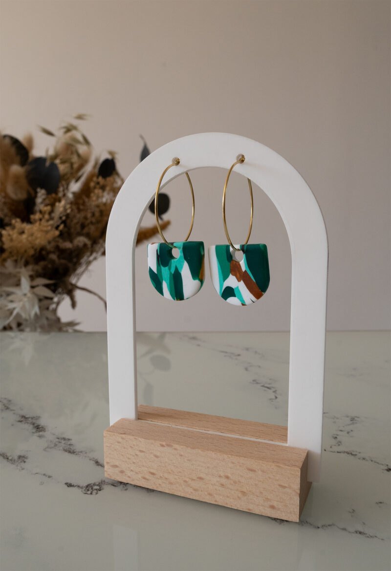 Apportez une touche de modernité à votre tenue grâce aux créoles avec pampille interchangeable, Inès. Ces boucles d’oreilles délicates se distinguent par un demi cercle marbré de différentes teintes de vert, de blanc et de doré. Il est posé sur une créole dorée ou argentée, à choisir selon vos préférences.