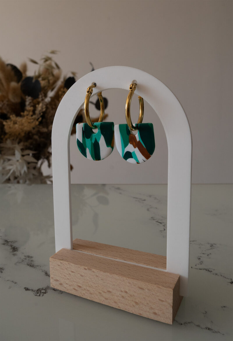 Apportez une touche de modernité à votre tenue grâce aux créoles avec pampille interchangeable, Inès. Ces boucles d’oreilles délicates se distinguent par un demi cercle marbré de différentes teintes de vert, de blanc et de doré. Il est posé sur une créole dorée ou argentée, à choisir selon vos préférences.