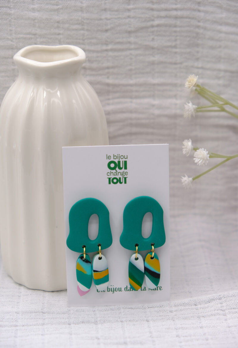Découvrez le modèle Lisette, des boucles d’oreilles pendantes qui associent une pièce principale aux courbes abstraites à deux petits rectangles arrondis qui dansent subtilement à chaque mouvement, tels des plumes. Confectionnées à la main en argile polymère, légères et audacieuses, les Lisette insufflent une touche de créativité à vos looks.