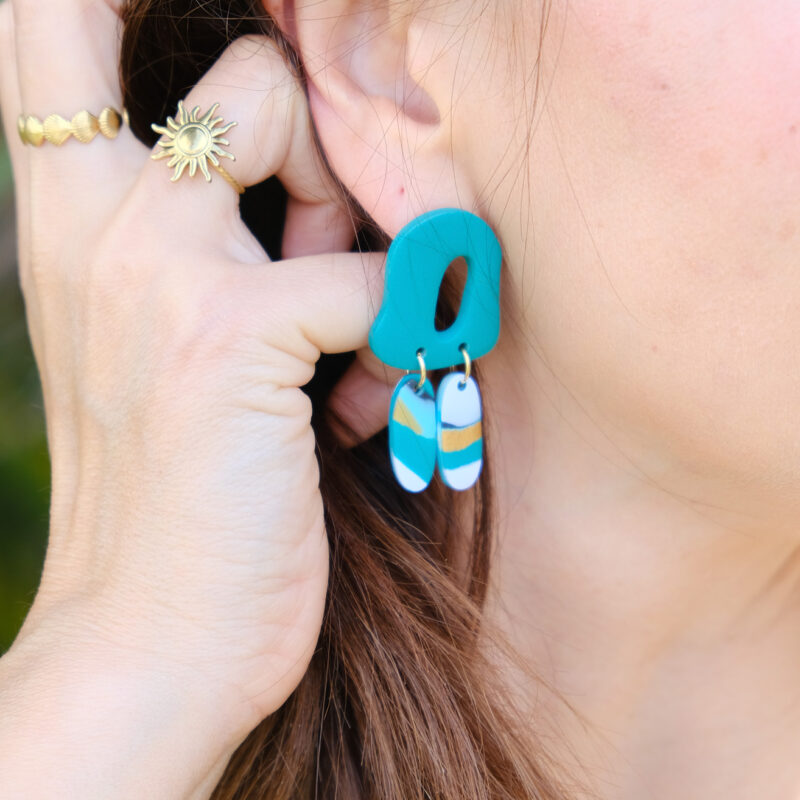 Découvrez le modèle Lisette, des boucles d’oreilles pendantes qui associent une pièce principale aux courbes abstraites à deux petits rectangles arrondis qui dansent subtilement à chaque mouvement, tels des plumes. Confectionnées à la main en argile polymère, légères et audacieuses, les Lisette insufflent une touche de créativité à vos looks.