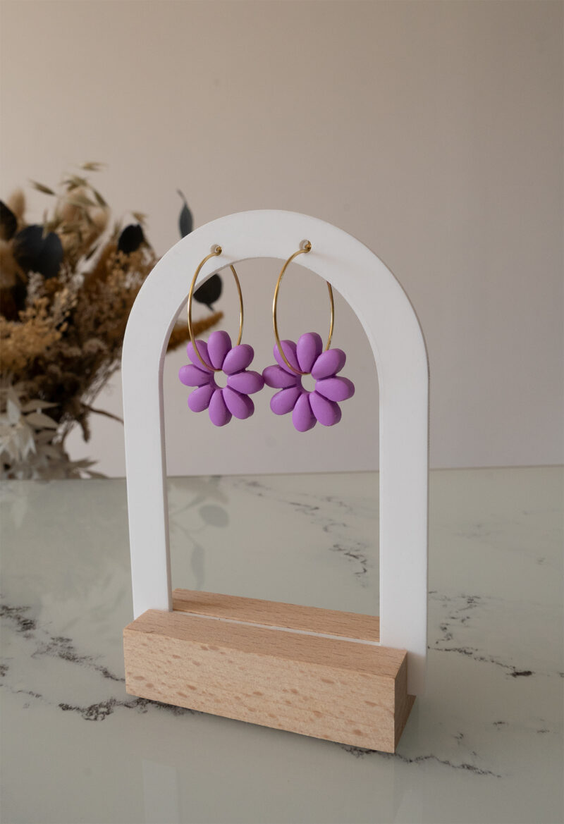 Apportez une touche de tendresse à votre tenue grâce aux créoles avec fleurs interchangeables, Marguerite. Ces boucles d’oreilles délicates se distinguent par une marguerite lilas posée sur une créole dorée ou argentée, à choisir selon vos préférences.