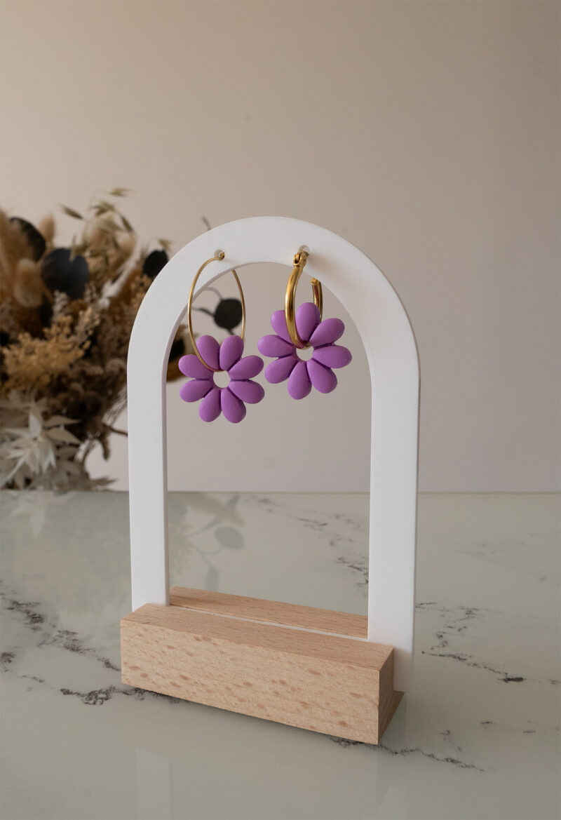 Apportez une touche de tendresse à votre tenue grâce aux créoles avec fleurs interchangeables, Marguerite. Ces boucles d’oreilles délicates se distinguent par une marguerite lilas posée sur une créole dorée ou argentée, à choisir selon vos préférences.