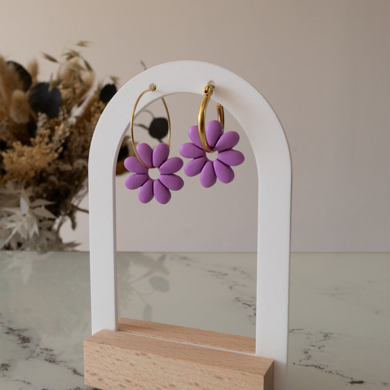 Apportez une touche de tendresse à votre tenue grâce aux créoles avec fleurs interchangeables, Marguerite. Ces boucles d’oreilles délicates se distinguent par une marguerite lilas posée sur une créole dorée ou argentée, à choisir selon vos préférences.