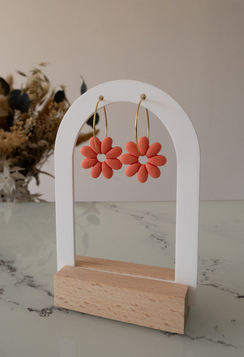 Apportez une touche de tendresse à votre tenue grâce aux créoles avec fleurs interchangeables, Marguerite. Ces boucles d’oreilles délicates se distinguent par une marguerite couleur pamplemousse, posée sur une créole dorée ou argentée, à choisir selon vos préférences.