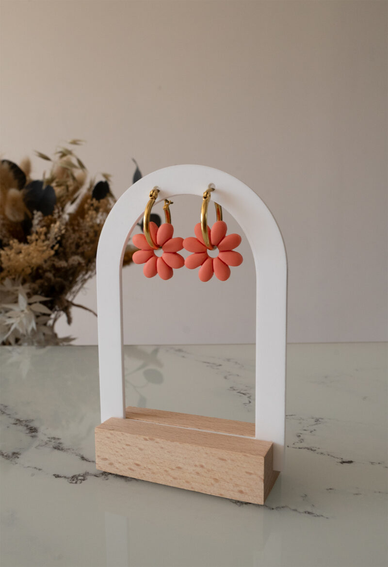 Apportez une touche de tendresse à votre tenue grâce aux créoles avec fleurs interchangeables, Marguerite. Ces boucles d’oreilles délicates se distinguent par une marguerite couleur pamplemousse, posée sur une créole dorée ou argentée, à choisir selon vos préférences.