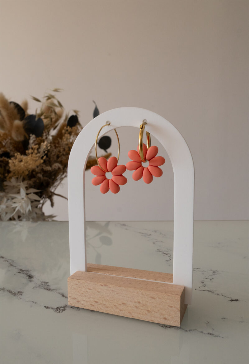 Apportez une touche de tendresse à votre tenue grâce aux créoles avec fleurs interchangeables, Marguerite. Ces boucles d’oreilles délicates se distinguent par une marguerite couleur pamplemousse, posée sur une créole dorée ou argentée, à choisir selon vos préférences.