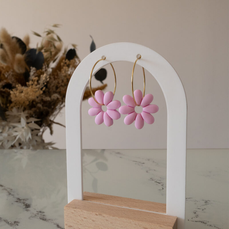 Apportez une touche de tendresse à votre tenue grâce aux créoles avec fleurs interchangeables, Marguerite. Ces boucles d’oreilles délicates se distinguent par une marguerite rose pale posée sur une créole dorée ou argentée, à choisir selon vos préférences.