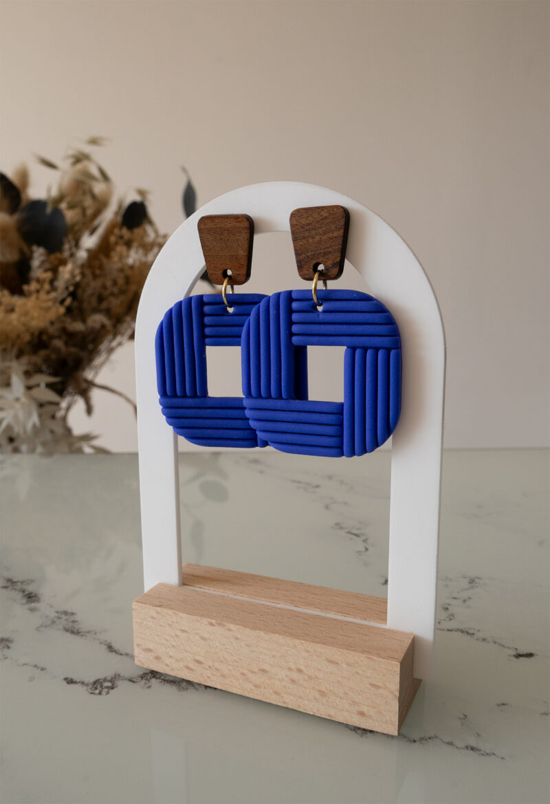 Découvrez Tara, des boucles d’oreilles pendantes qui associent une pièce rectangulaire en bois à un carré aux bord arrondi façonné à la main, en argile polymère bleu roi.Ultra-légères et confortables, ces boucles faites main sont conçues pour révéler votre singularité et donner du caractère à votre tenue.