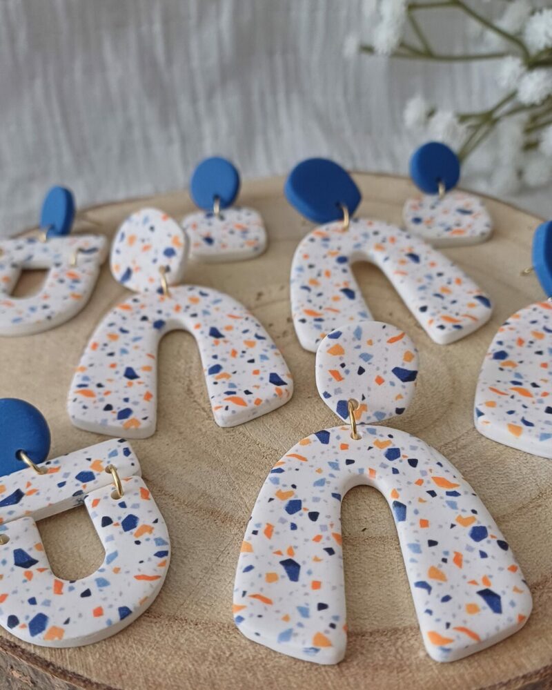 Des grosses boucles d'oreilles faites main avec arche, en terrazzo bleu et orange. Des boucles d'oreilles pendantes, tendance à l'allure bohème. A s'offrir sur le site Un Bijou dans la Mare.