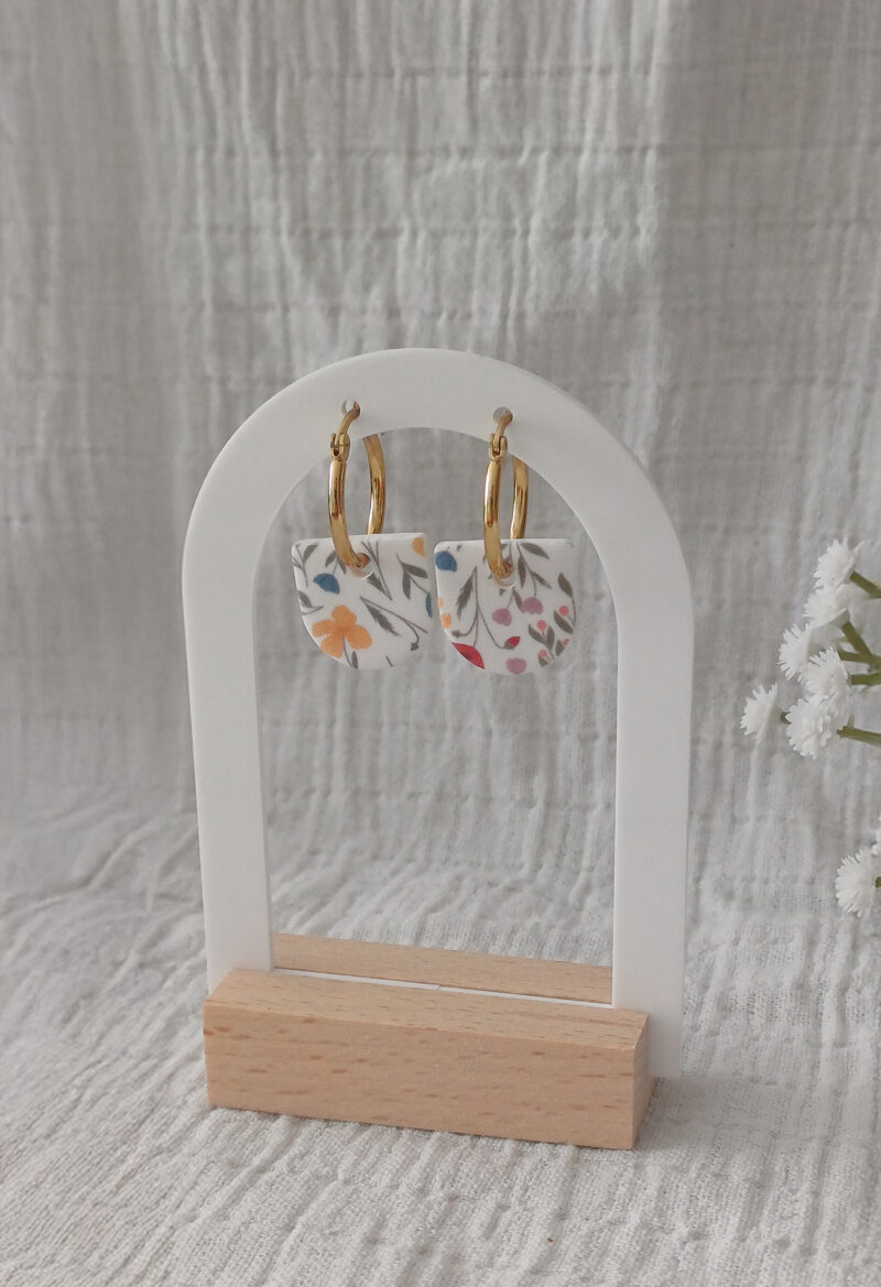Apportez une touche de poésie à votre tenue grâce aux créoles avec pampille interchangeable, Inès. Ces boucles d’oreilles délicates se distinguent par un demi cercle avec un motif floral rare et breveté aux couleurs douces et apaisantes. Il est posé sur une créole dorée ou argentée, à choisir selon vos préférences. Polyvalentes, ultra légères et confortables, elles sublimeront aussi bien une tenue décontractée qu'un style plus sophistiqué. Les créoles sont en acier inoxydable (sans plomb, sans cadmium, sans nickel), les pampilles, elles, sont faites main en argile polymère.