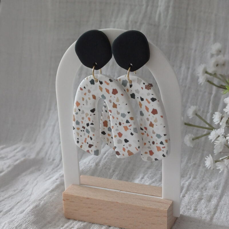 Des grosses boucles d'oreilles faites main avec arche, en terrazzo noir et marron. Des boucles d'oreilles pendantes, tendance à l'allure bohème. A s'offrir sur le site Un Bijou dans la Mare.