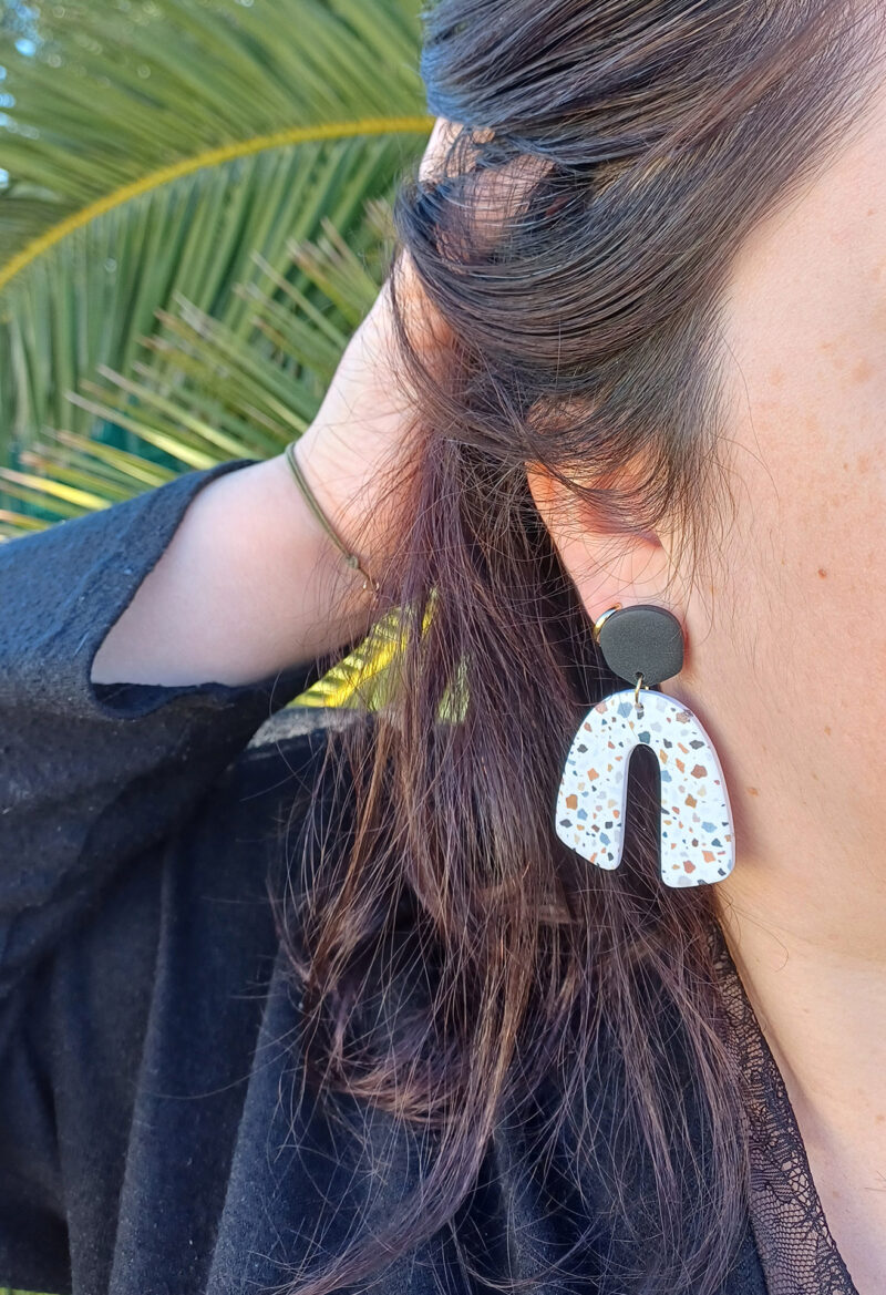 Des grosses boucles d'oreilles faites main avec arche, en terrazzo noir et marron. Des boucles d'oreilles pendantes, tendance à l'allure bohème. A s'offrir sur le site Un Bijou dans la Mare.