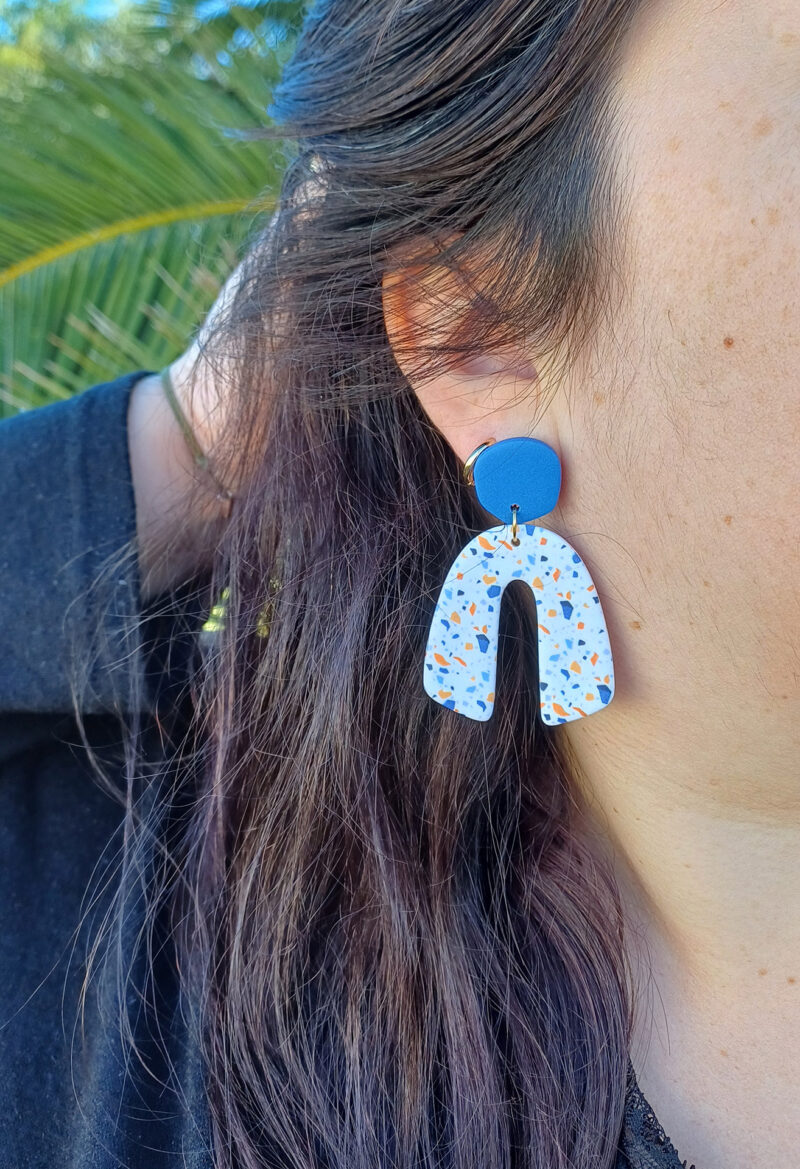 Des grosses boucles d'oreilles faites main avec arche, en terrazzo bleu et orange. Des boucles d'oreilles pendantes, tendance à l'allure bohème. A s'offrir sur le site Un Bijou dans la Mare.