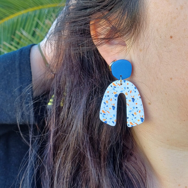 Des grosses boucles d'oreilles faites main avec arche, en terrazzo bleu et orange. Des boucles d'oreilles pendantes, tendance à l'allure bohème. A s'offrir sur le site Un Bijou dans la Mare.