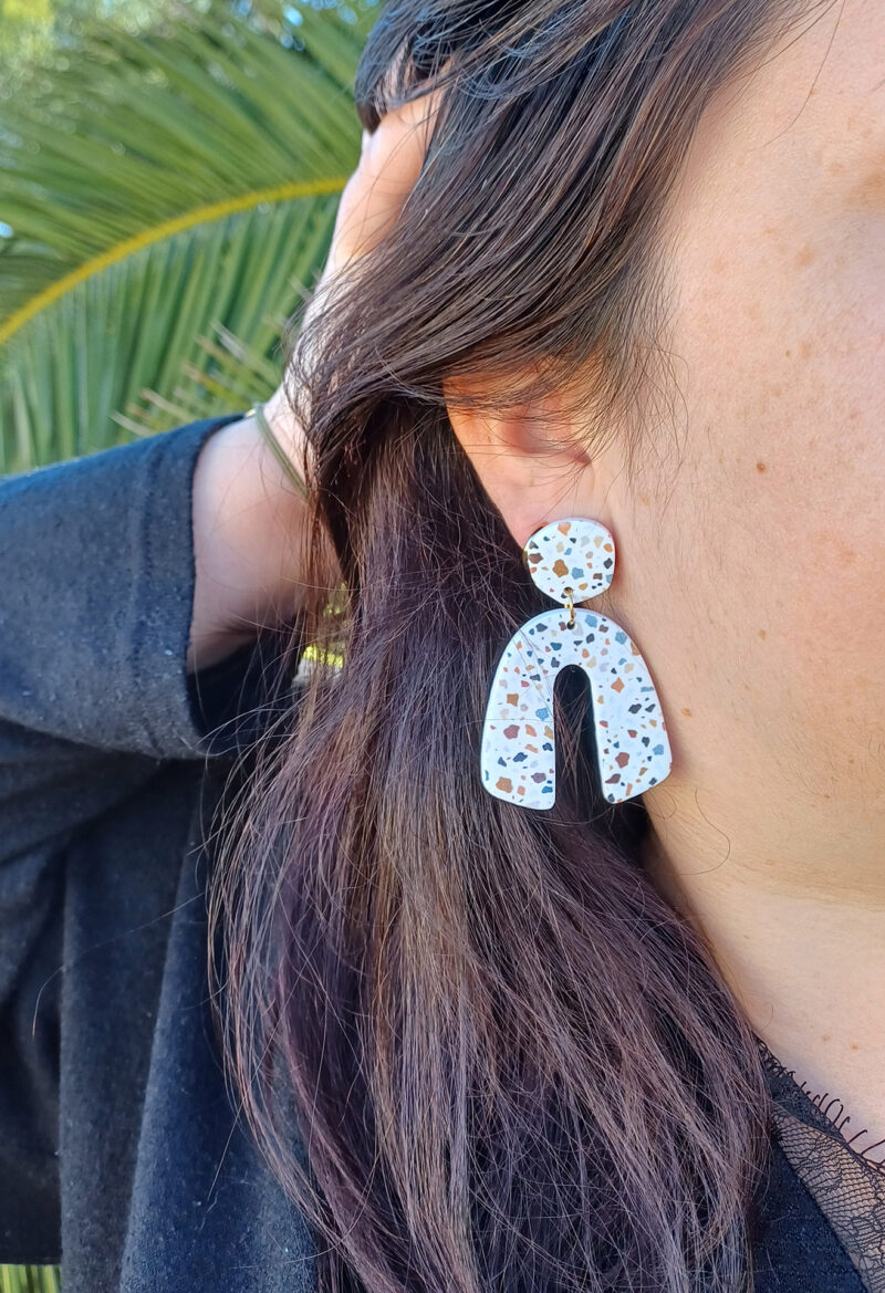 Des grosses boucles d'oreilles faites main avec arche, en terrazzo noir et marron. Des boucles d'oreilles pendantes, tendance à l'allure bohème. A s'offrir sur le site Un Bijou dans la Mare.