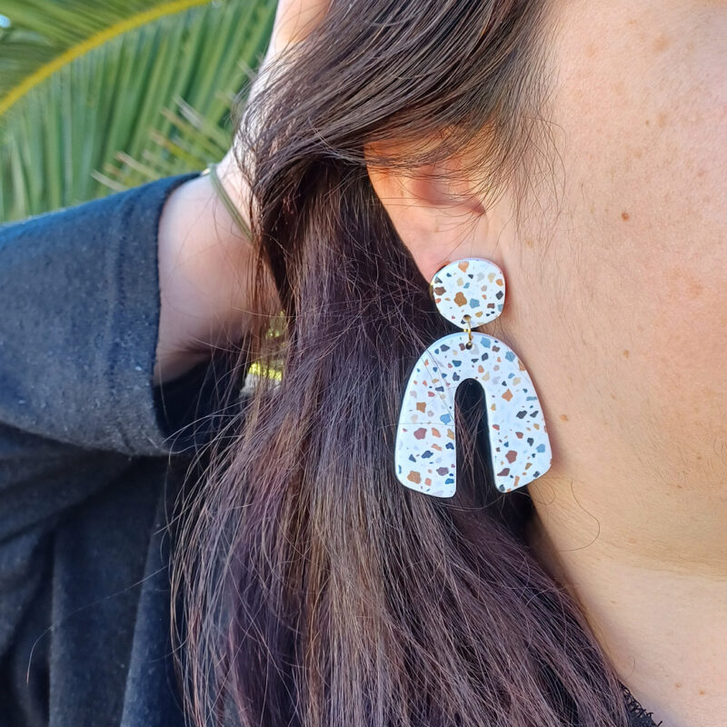 Des grosses boucles d'oreilles faites main avec arche, en terrazzo noir et marron. Des boucles d'oreilles pendantes, tendance à l'allure bohème. A s'offrir sur le site Un Bijou dans la Mare.