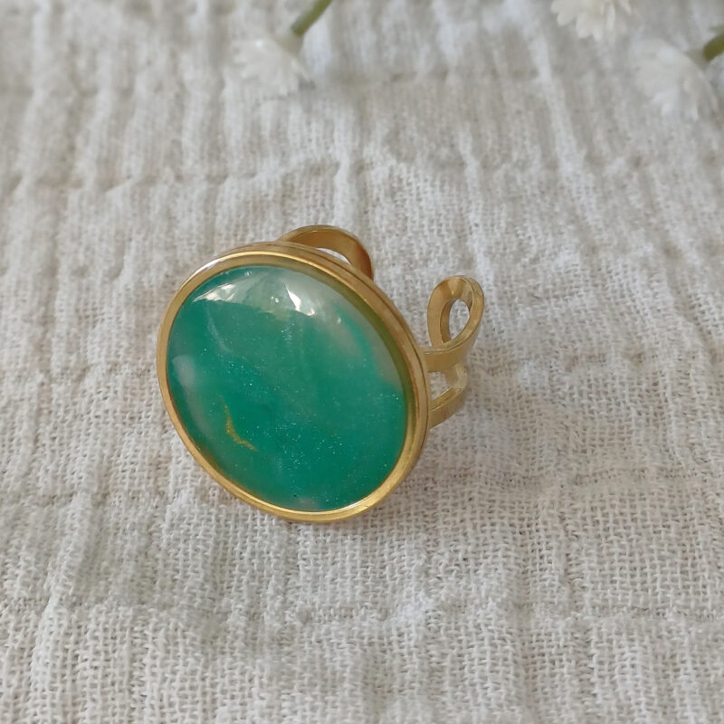 Façonnée à la main en argile polymère transparente, la bague Alice dévoile à la cuisson des reflets uniques, inspirés de la pierre Amazonite : un vert apaisant mêlé à des nuances dorées et laiteuses. Montée sur un anneau ajustable en acier inoxydable 201 plaqué or, hypoallergénique et durable, la bague Alice s’adapte à toutes les mains avec élégance.