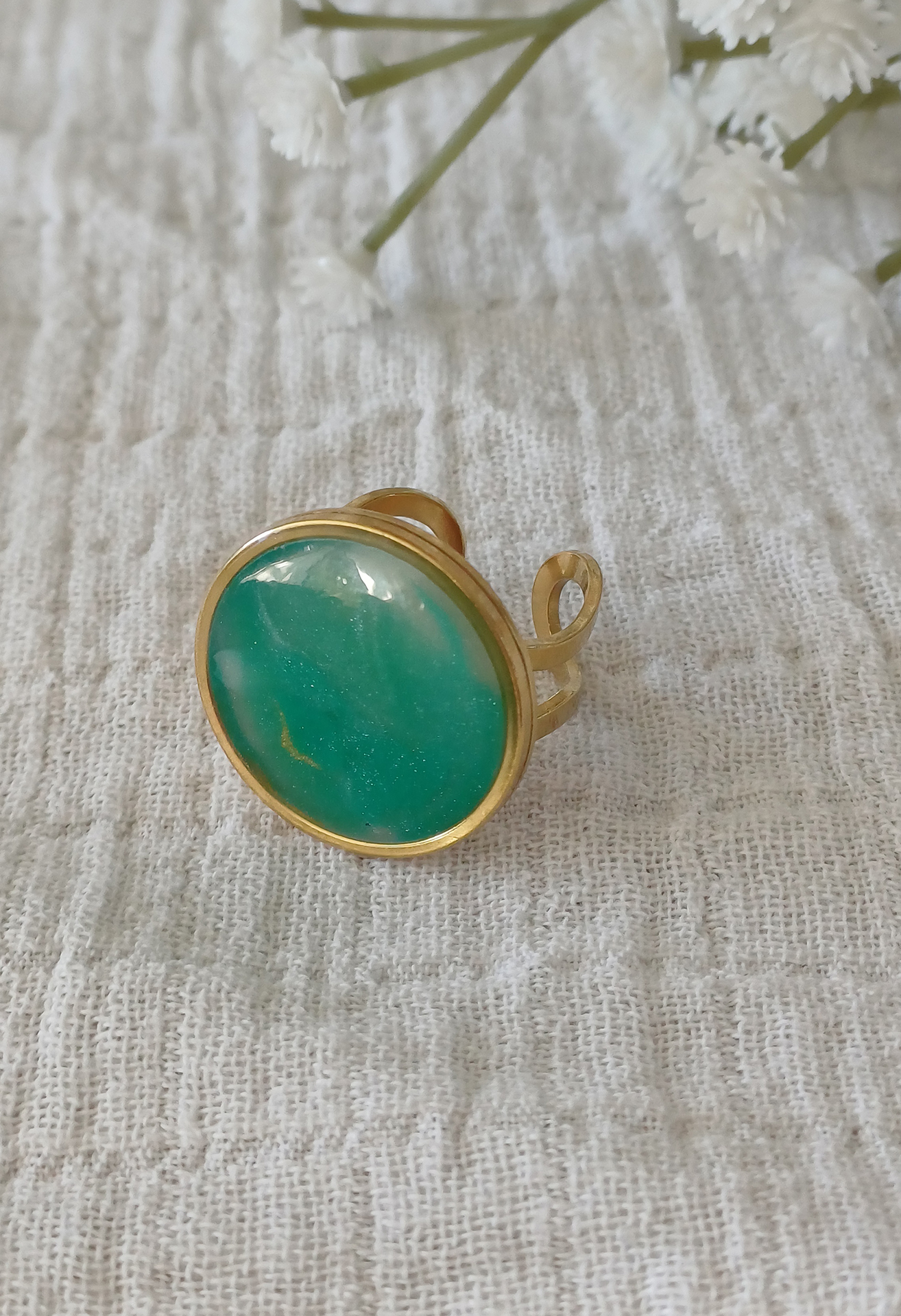 Façonnée à la main en argile polymère transparente, la bague Alice dévoile à la cuisson des reflets uniques, inspirés de la pierre Amazonite : un vert apaisant mêlé à des nuances dorées et laiteuses. Montée sur un anneau ajustable en acier inoxydable 201 plaqué or, hypoallergénique et durable, la bague Alice s’adapte à toutes les mains avec élégance.