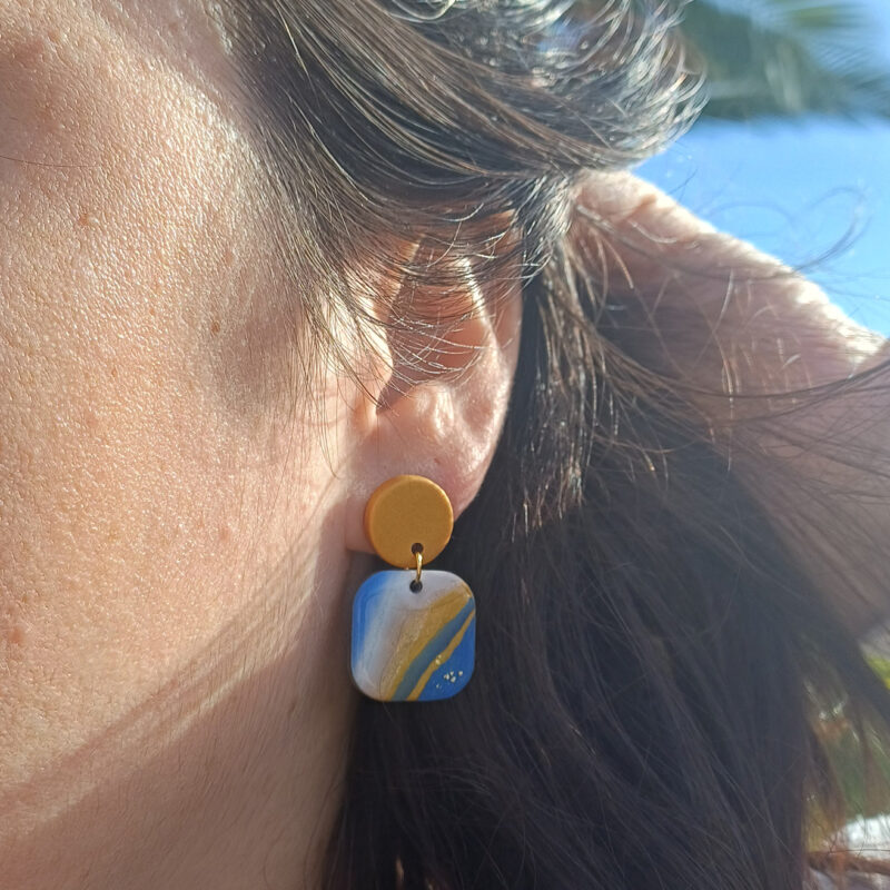 Ajoutez une touche de modernité minimaliste à votre style avec les boucles d’oreilles faites main Élodie. Ces pièces uniques associent un rond d’un beau doré nacré à un carré aux bords arrondis, marbré avec 3 couleurs de bleu différents, du blanc du noir et du doré nacré. Parfaites pour toutes les occasions, elles apportent une subtilité contemporaine à vos tenues, qu’elles soient casual ou habillées.