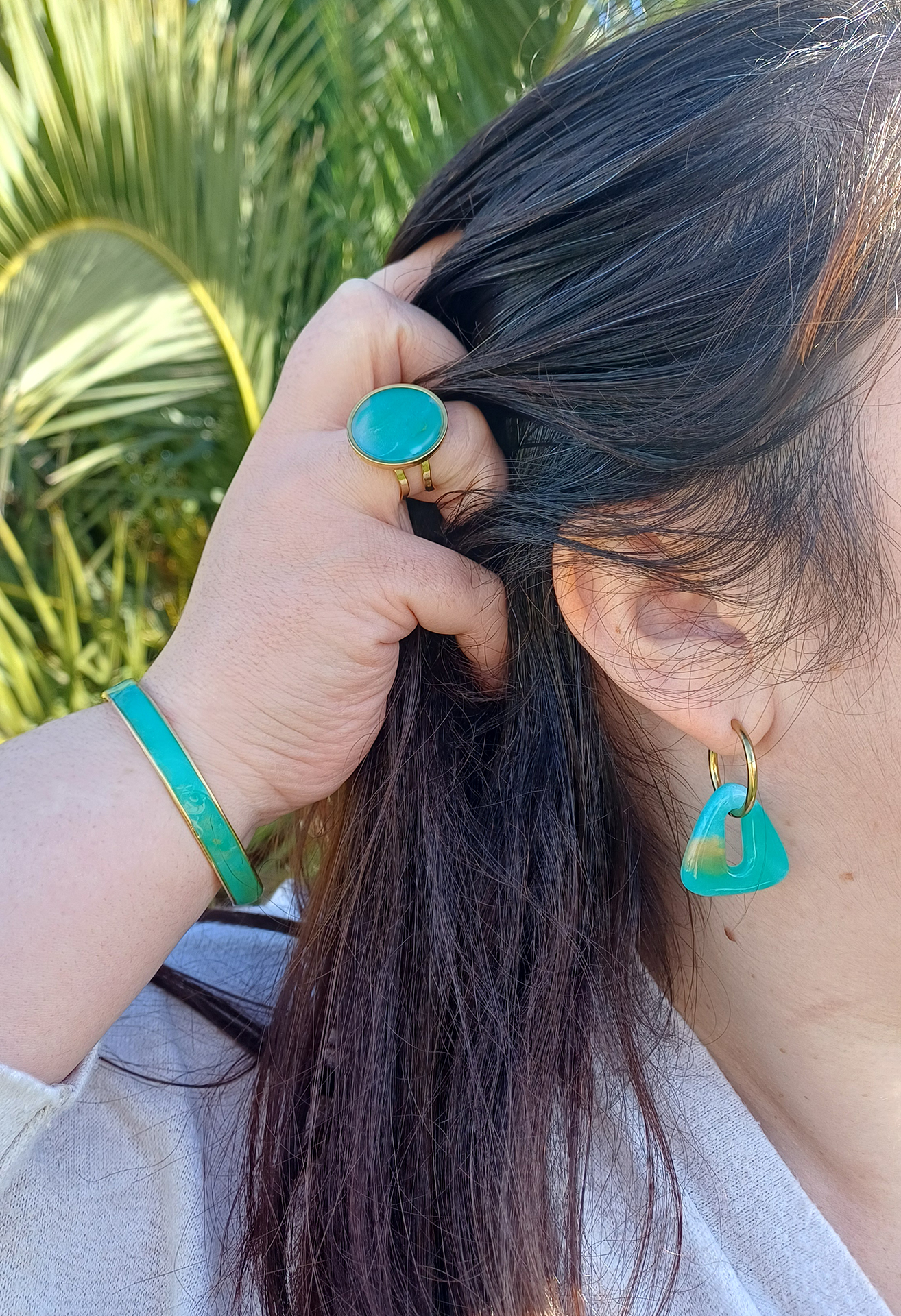 Le jonc Virginie en argile polymère et laiton doré allie finesse et caractère dans un design à la fois moderne et intemporel. Son cabochon en argile polymère transparente, façonné à la main, révèle des nuances inspirées de la pierre Amazonite avec son mélange subtil de vert, de blanc et de doré qui capte la lumière et change selon l’angle. Ce jonc s’adapte confortablement à tous les poignets. Retrouvez également la bague et les créoles intergangeables pour faire une parure.