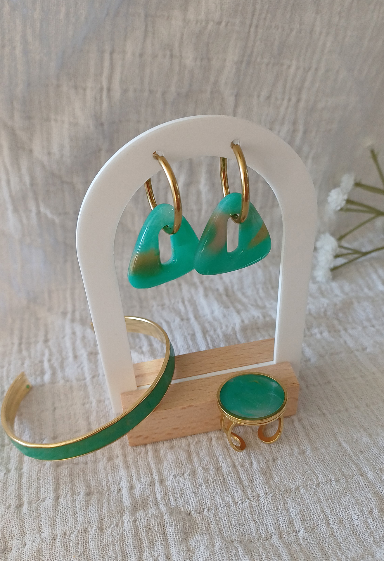 Le jonc Virginie en argile polymère et laiton doré allie finesse et caractère dans un design à la fois moderne et intemporel. Son cabochon en argile polymère transparente, façonné à la main, révèle des nuances inspirées de la pierre Amazonite avec son mélange subtil de vert, de blanc et de doré qui capte la lumière et change selon l’angle. Ce jonc s’adapte confortablement à tous les poignets. Retrouvez également la bague et les créoles intergangeables pour faire une parure.